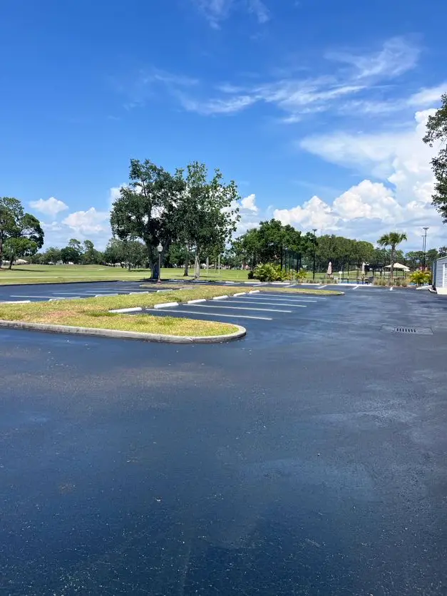 Freshly sealcoated commercial parking lot with white striping lines at a golf course facility in Tampa, Florida by Radiant Striping