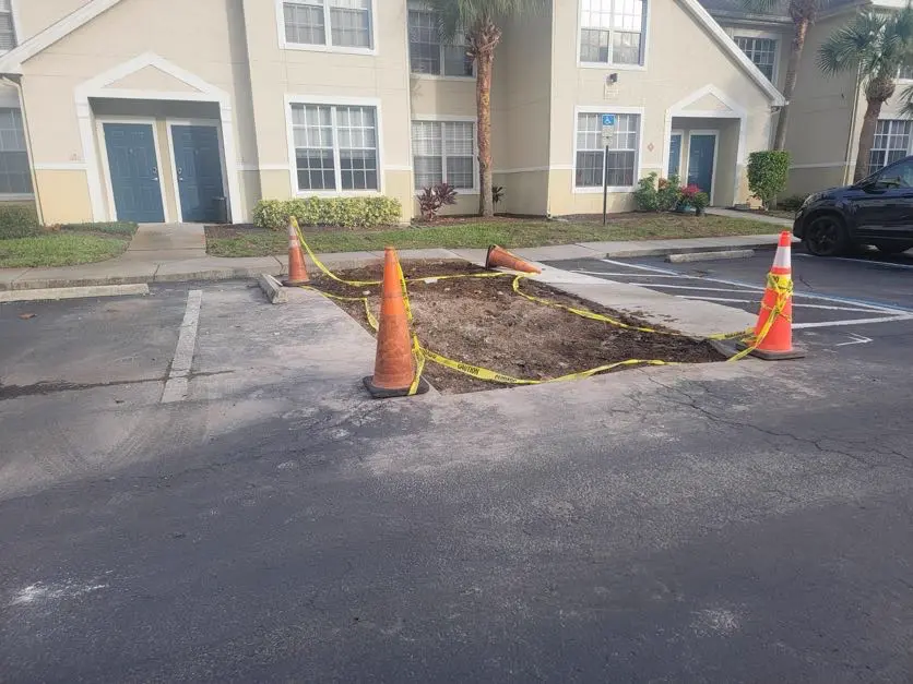 Asphalt repair in progress with safety cones at Tampa apartment complex by Radiant Striping